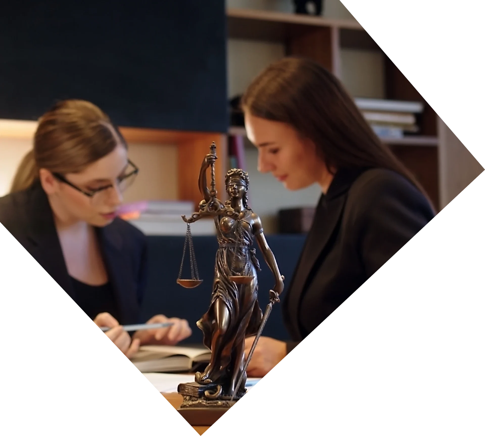 Lady Justice statue with two women working